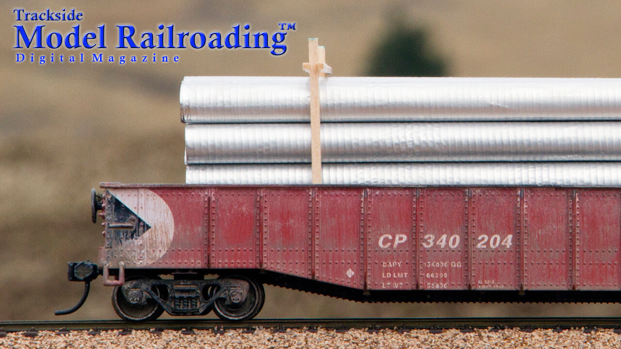 Close up of an HO scale gondola loaded with the galvanized corrugated pipes from Novembers Trackside Model Railroading digital magazine.. 